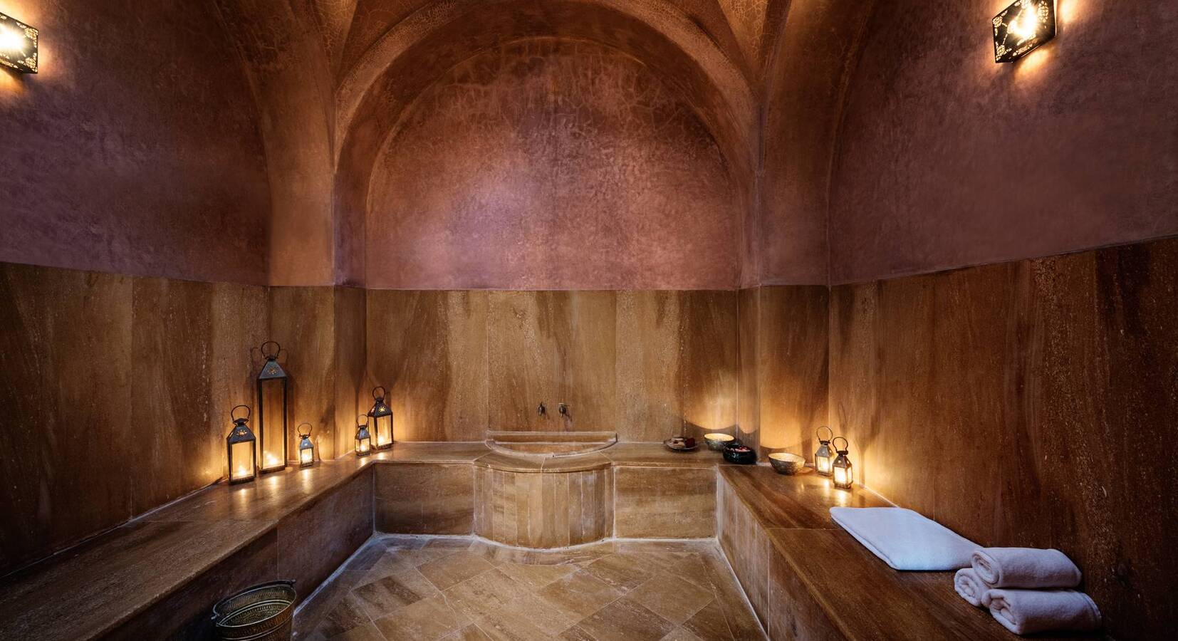 Hammam marocain aux murs de tadelakt, éclairé à la lanterne
